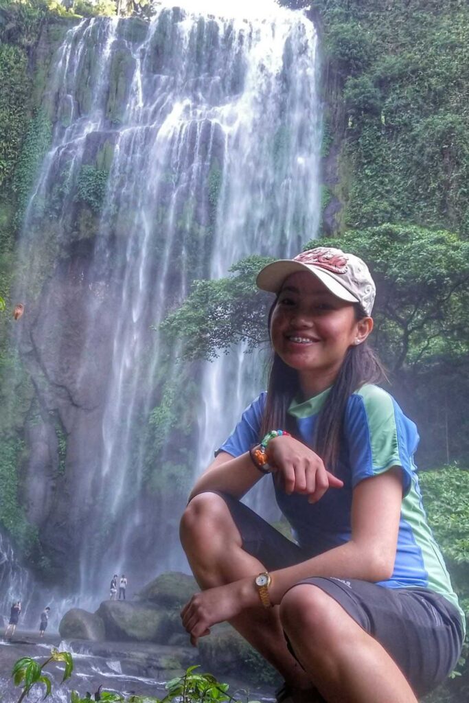 A woman's picture with a view of Hulugan Falls behind her.